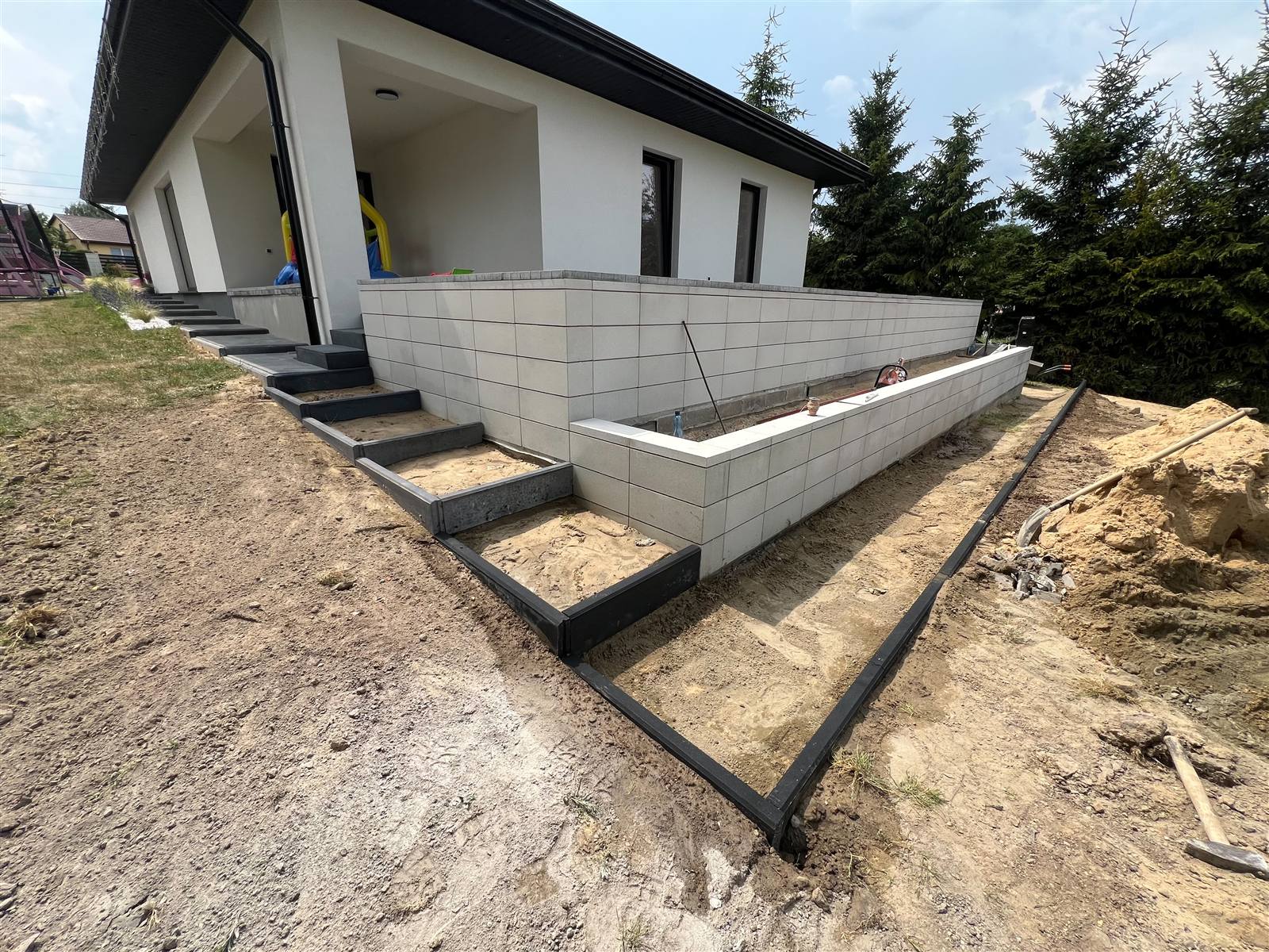 Murek oporowy z bloczków betonowych ze schodami i obrzeżami